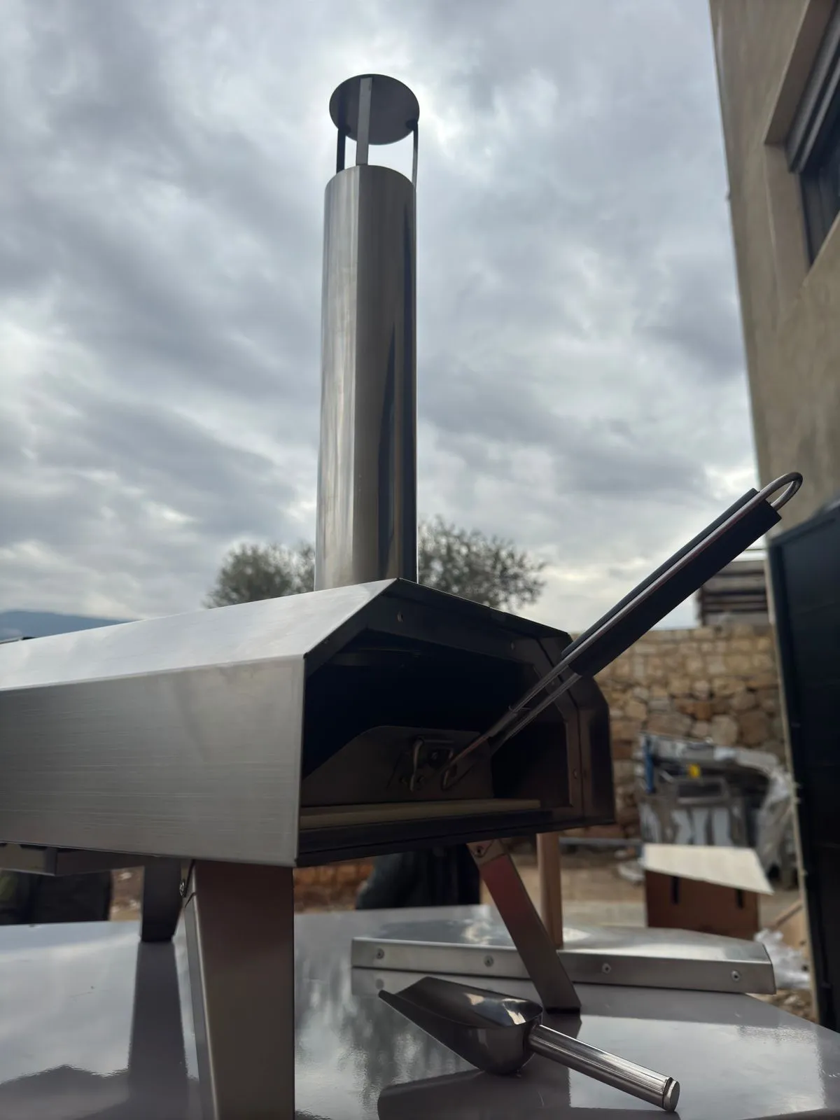 The pizza oven’s mouth with the peel and scoop, chimney above