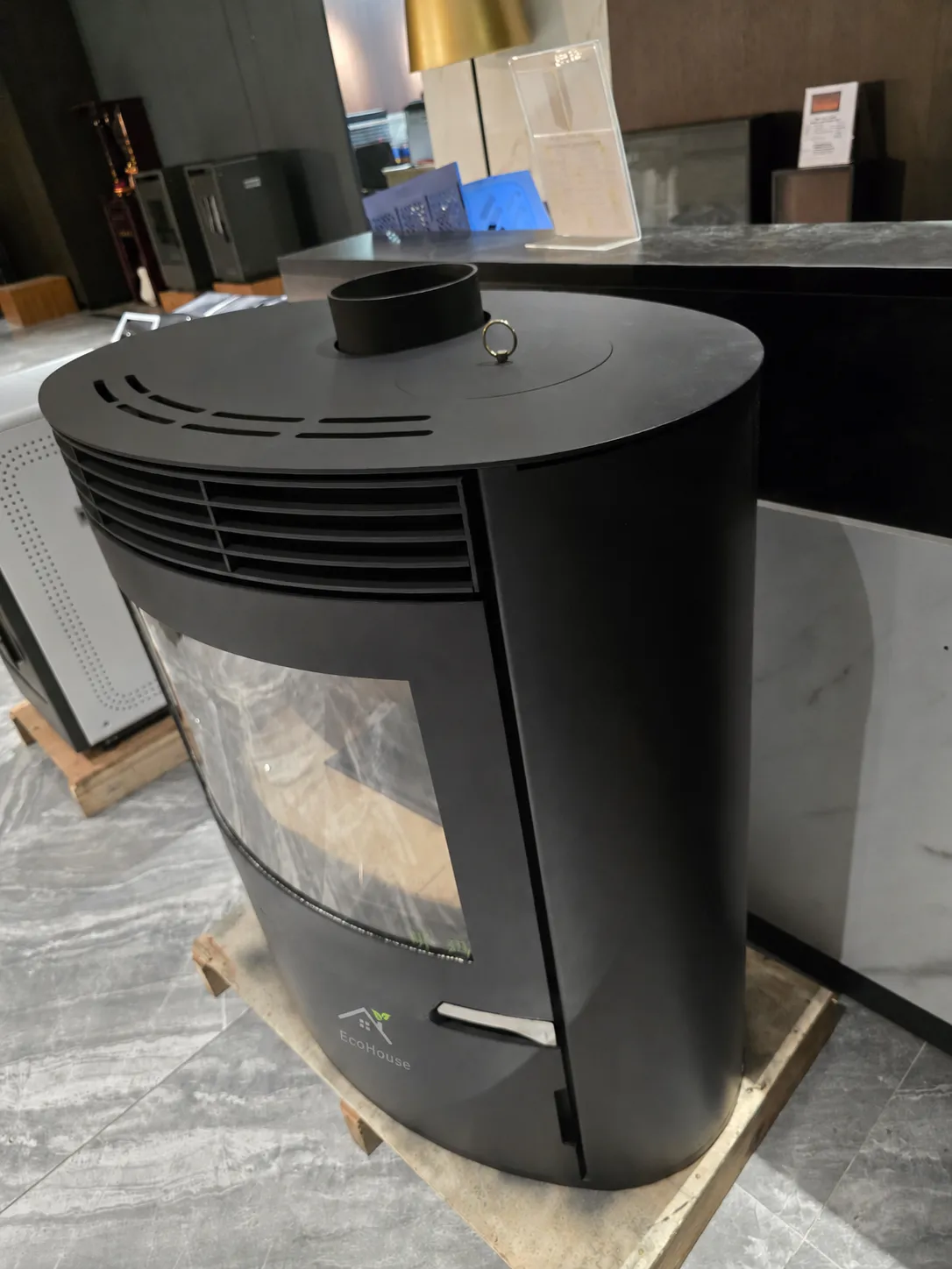 Black curved pellet stove from an angle showing its oval cooktop in a showroom
