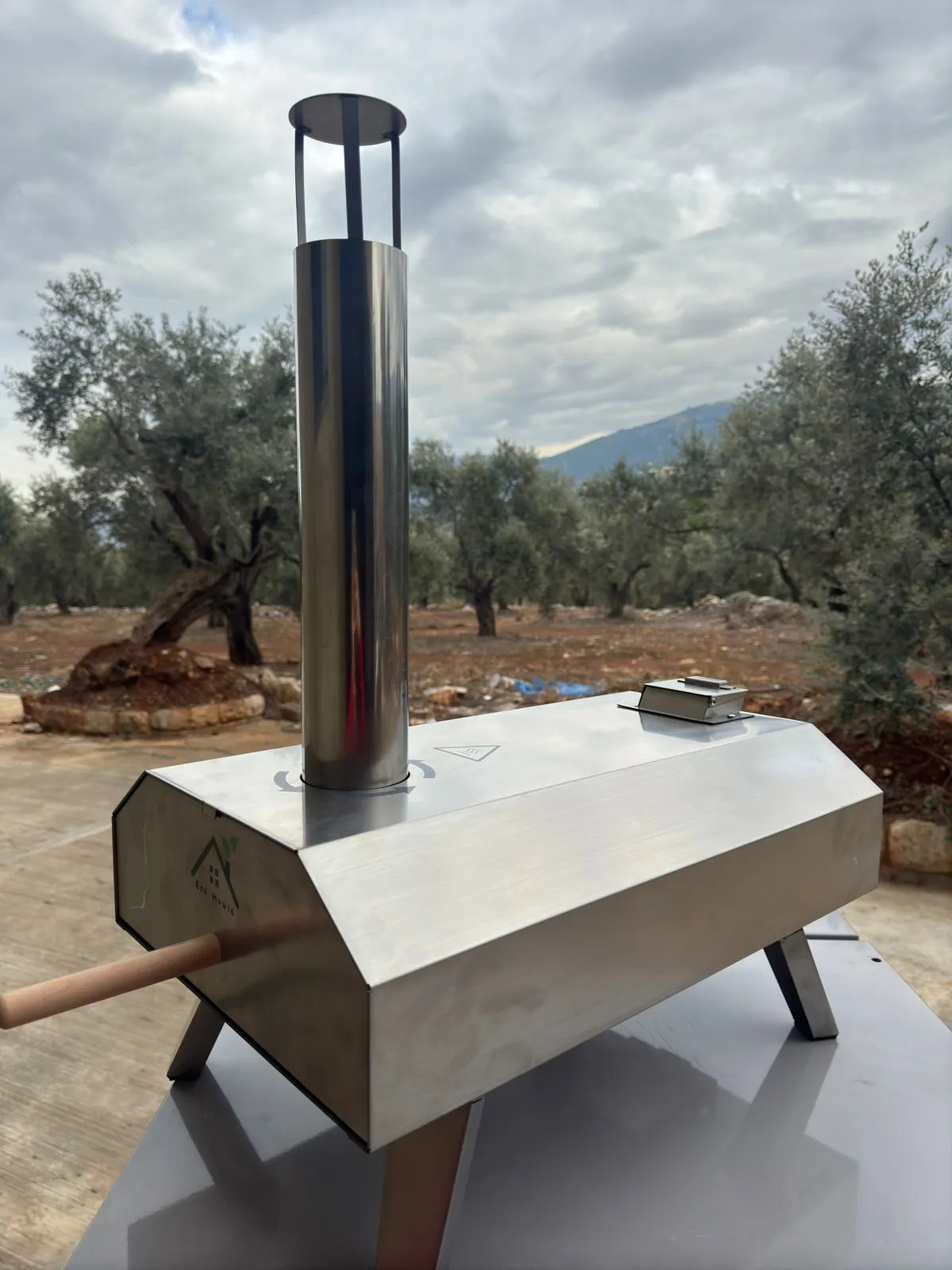 Side profile of the pellet pizza oven with its chimney and wooden handle